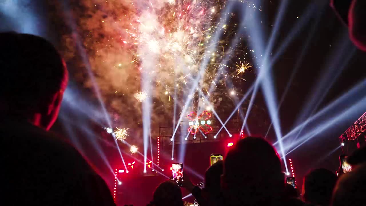 Fireworks and searchlights over a festival mainstage
