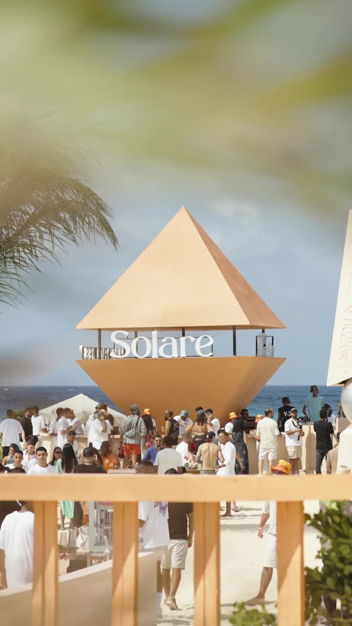 A DJ playing on a beach stage in daylight