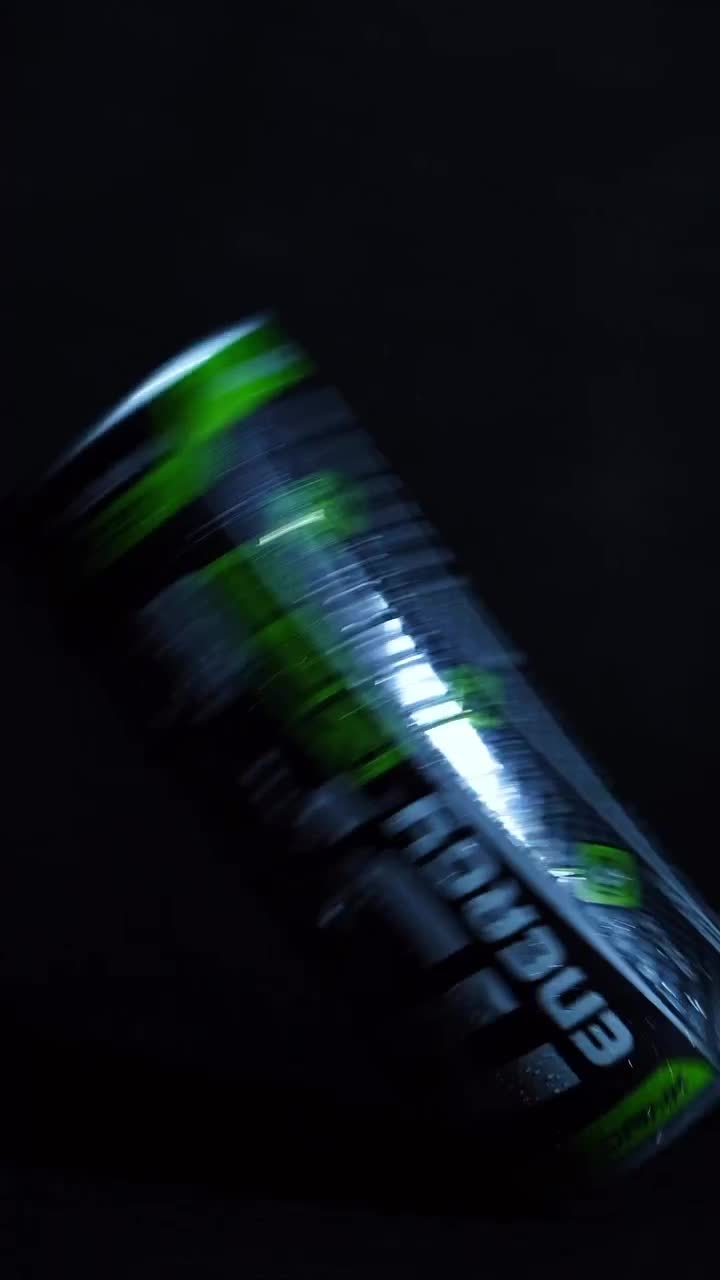 A neon-lit energy drink can with smoke and droplets