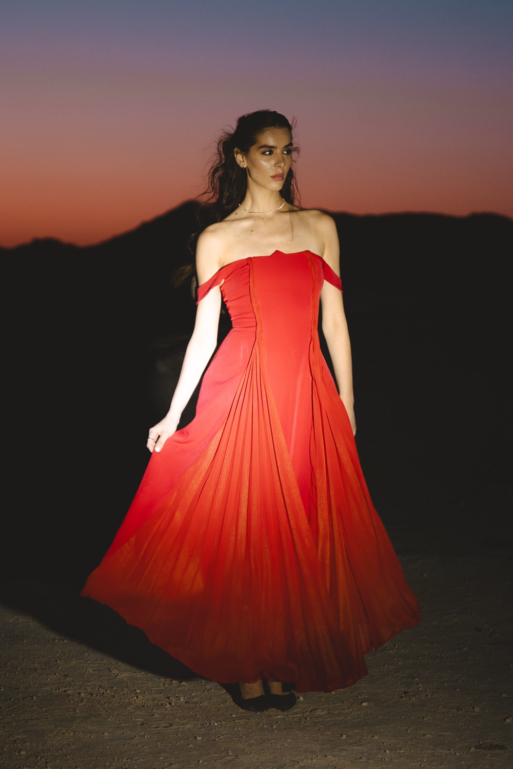 A model in a red gown photographed at dusk