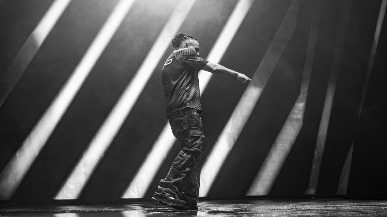 A performer in black and white between shafts of light