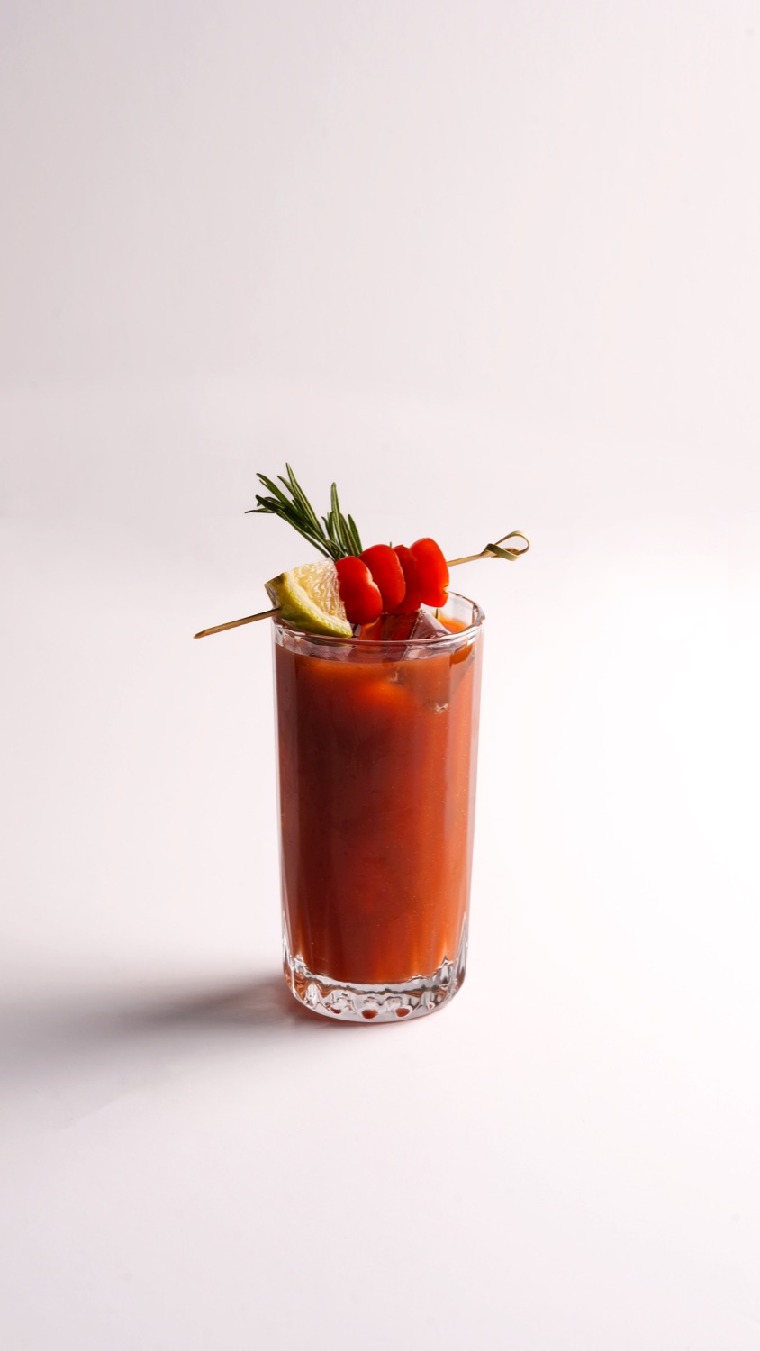 A bloody mary with a rose garnish on white