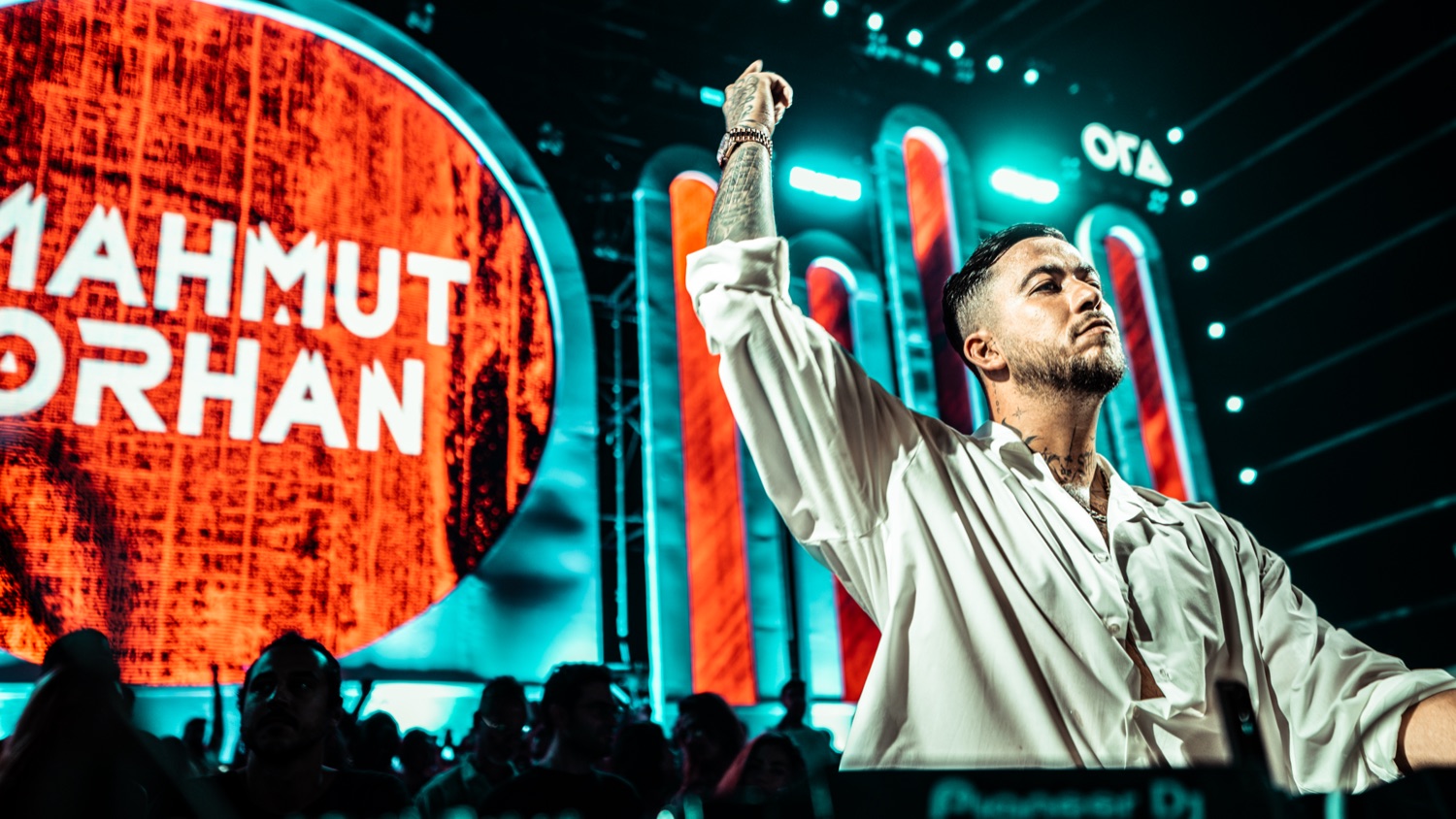 Mahmut Orhan performing beside his name in neon