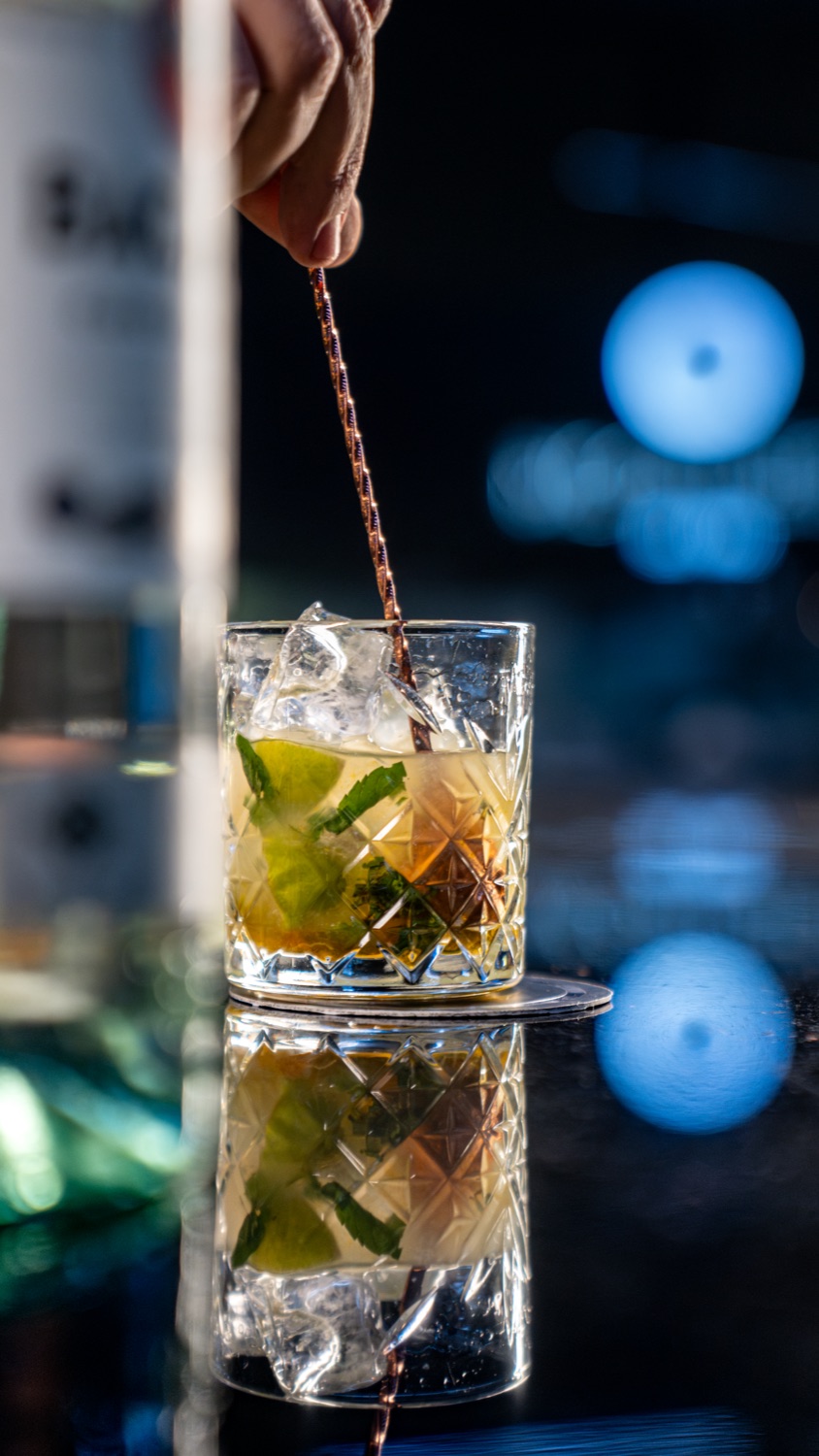 A bartender stirring a cocktail, blue night light