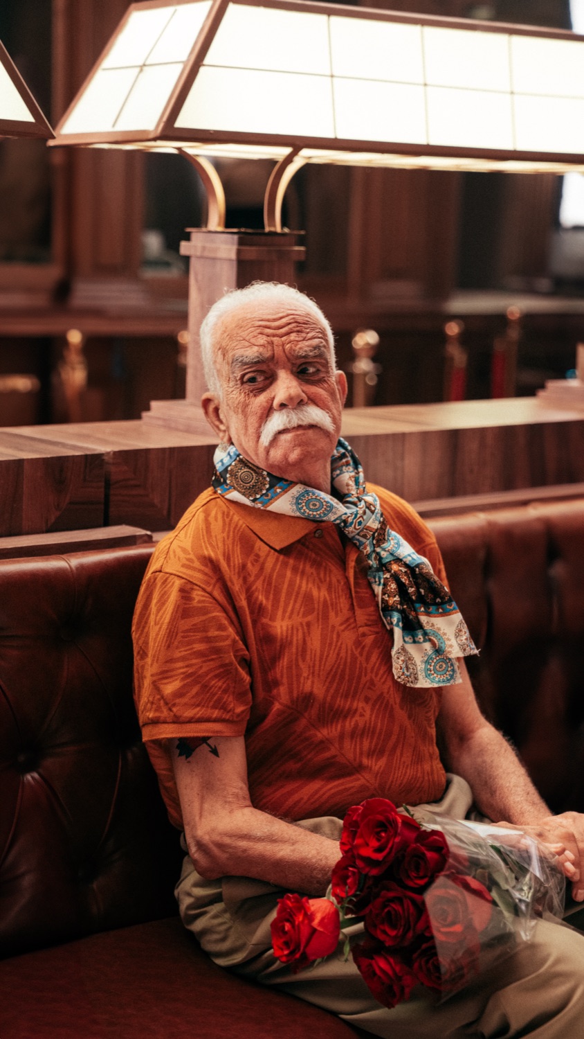 An elderly man holding red roses