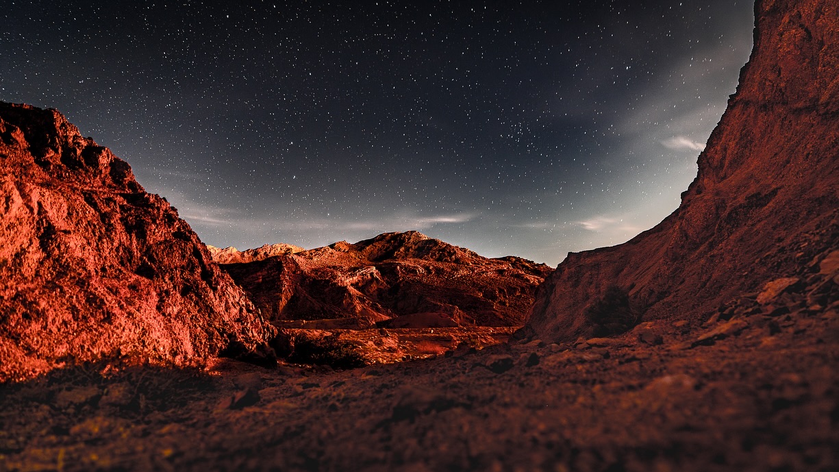 A red desert canyon under a starry sky