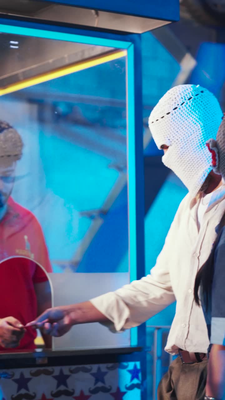 A figure in a crochet balaclava at a funfair at night